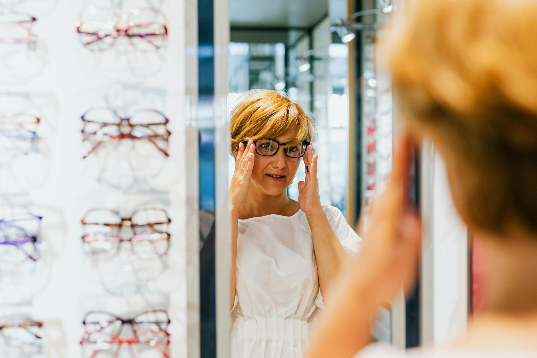an optician in a shop selling glasses to a client